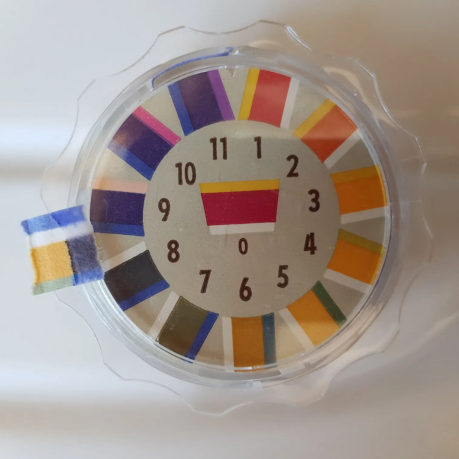 Bandelette de papier pH posée à côté de l'échelle de teintes de référence.