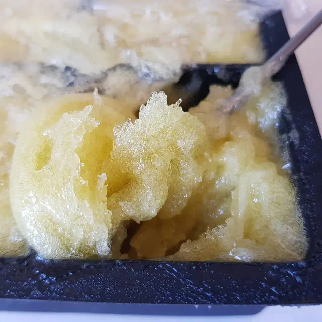 Moule à glaçon carré rempli d'une pâte jaune criblé de bulles.