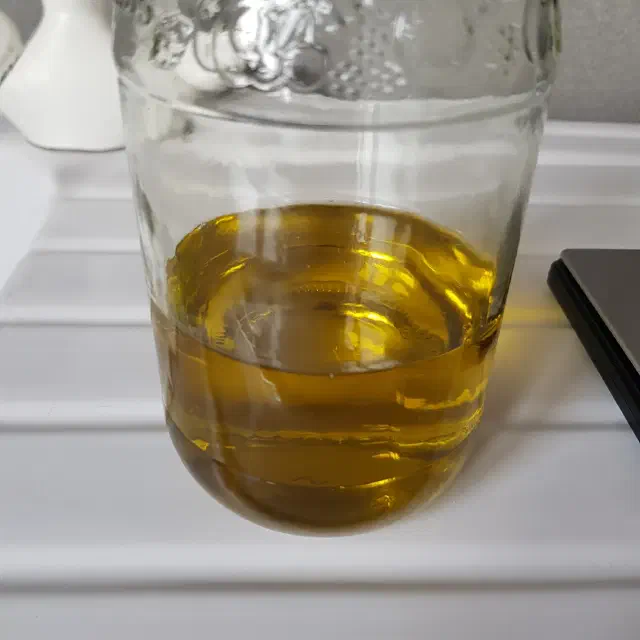 Mélange d'huiles végétales de couleur verte dans un bocal en verre.
