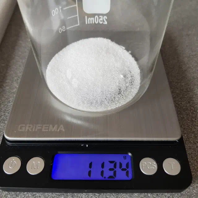 Bécher contenant une poudre blanche placé sur une balance.